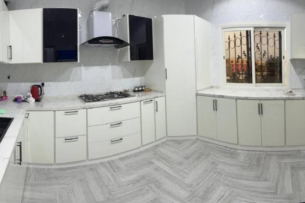 a kitchen with white cabinets and a wooden floor at شقة فاخرة بأبها in Abha