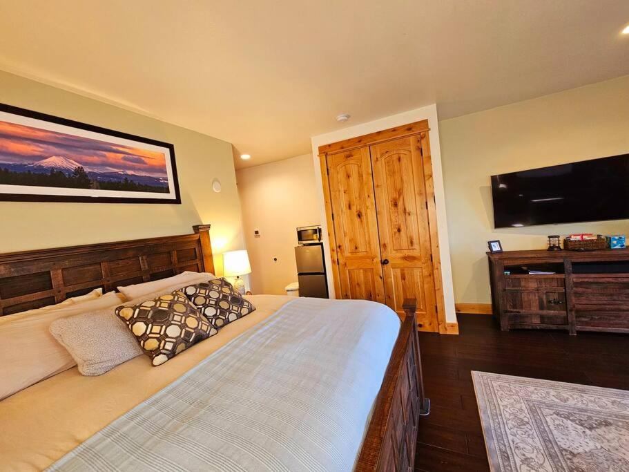 a bedroom with a large bed and a flat screen tv at Beautiful Riverfront Near Mt Bachelor with Hot Tub in Bend