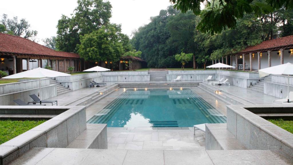 a swimming pool with tables and chairs in a yard at Heritage Madurai in Madurai