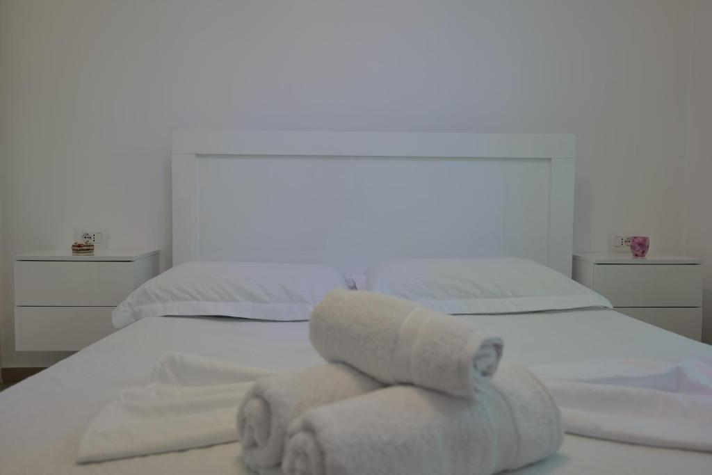 a white bedroom with two towels on a bed at Loris Apartment in Sarandë