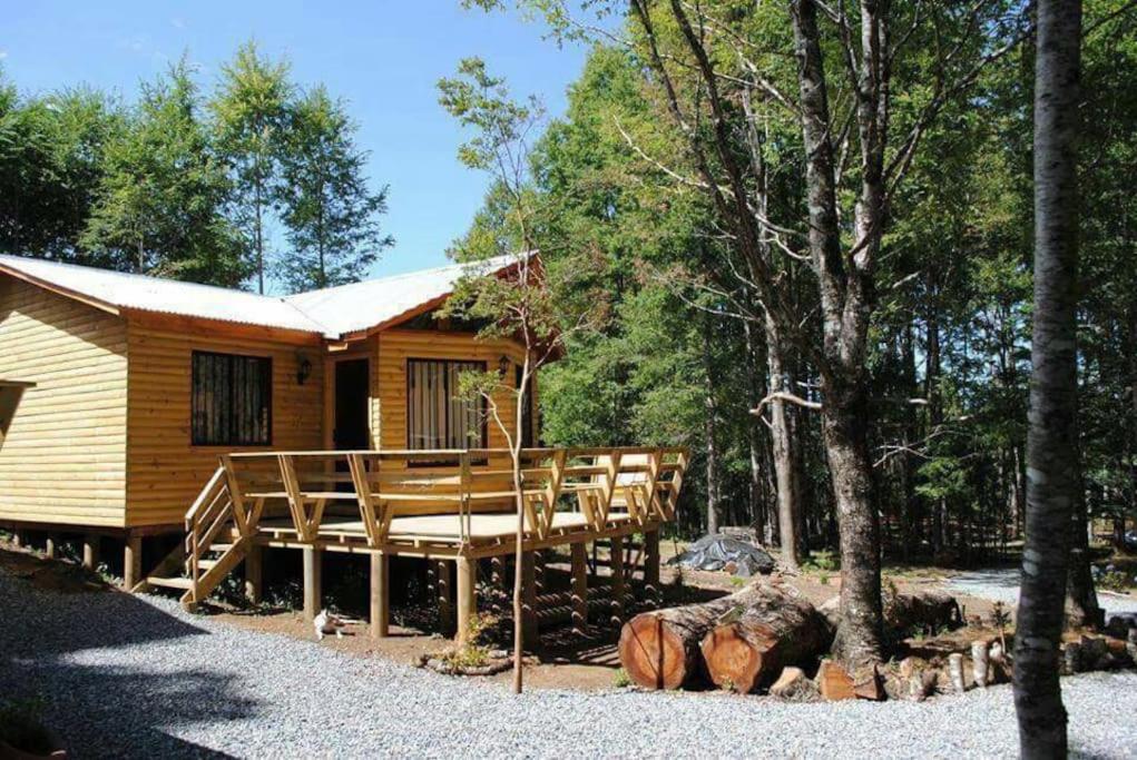 a log cabin with a porch in the woods at Cabañas villa ojen la pinta número 4 in Caburgua