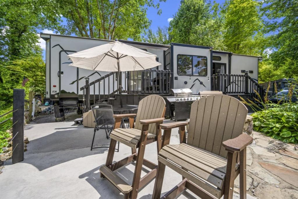 a caravan with a table and chairs and an umbrella at Creekside Glamping Resort- Fishing Pond, Mini Golf, Game Room, Pet Friendly in Gatlinburg