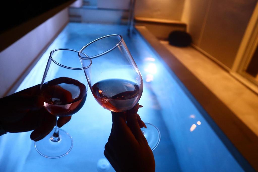 a person holding a glass of wine next to a pool at Rhotheon Suites in Ialysos Rhodes - private pool in selected rooms in Ialysos