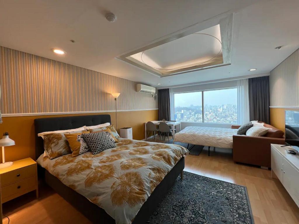 Un dormitorio con una cama y un sofá y una ventana. en Oasis Hongdae City View, en Seúl