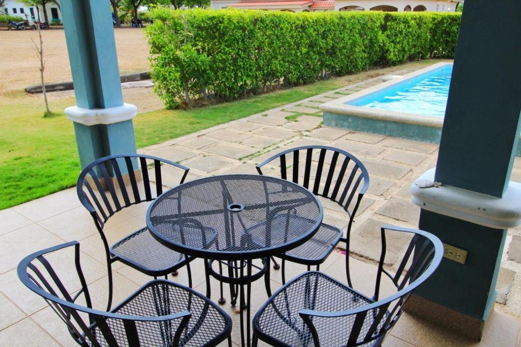 a table with four chairs and a pool at Casa Brisa, Gran Pacifica in Managua