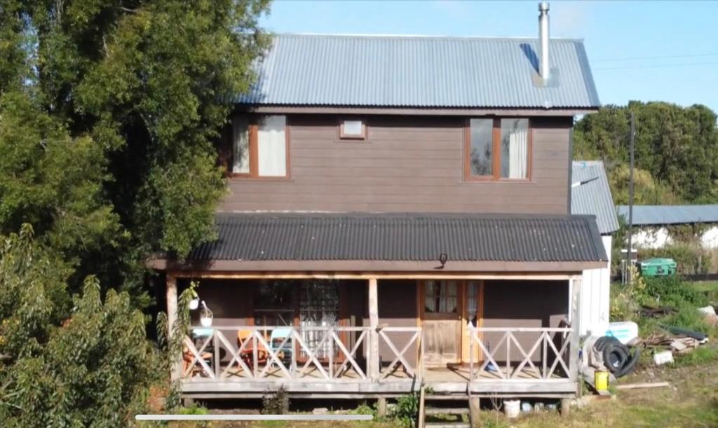 een klein huis met een veranda en een balkon bij Chon-Vilú in Chonchi