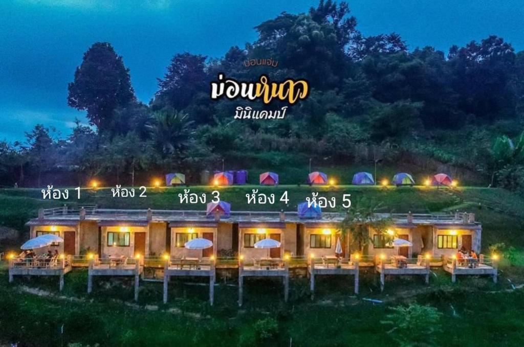 Mon Jamにあるม่อนหนาวOrdinary roomの夜間のテーブルと傘を備えた建物