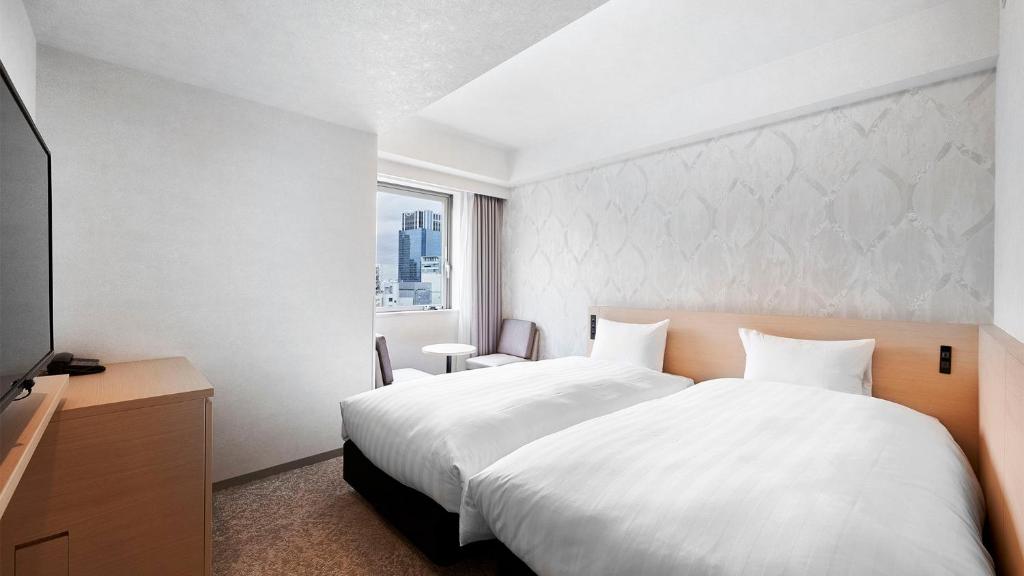 a bedroom with a large white bed and a window at Daiwa Roynet Hotel Kawasaki in Kawasaki