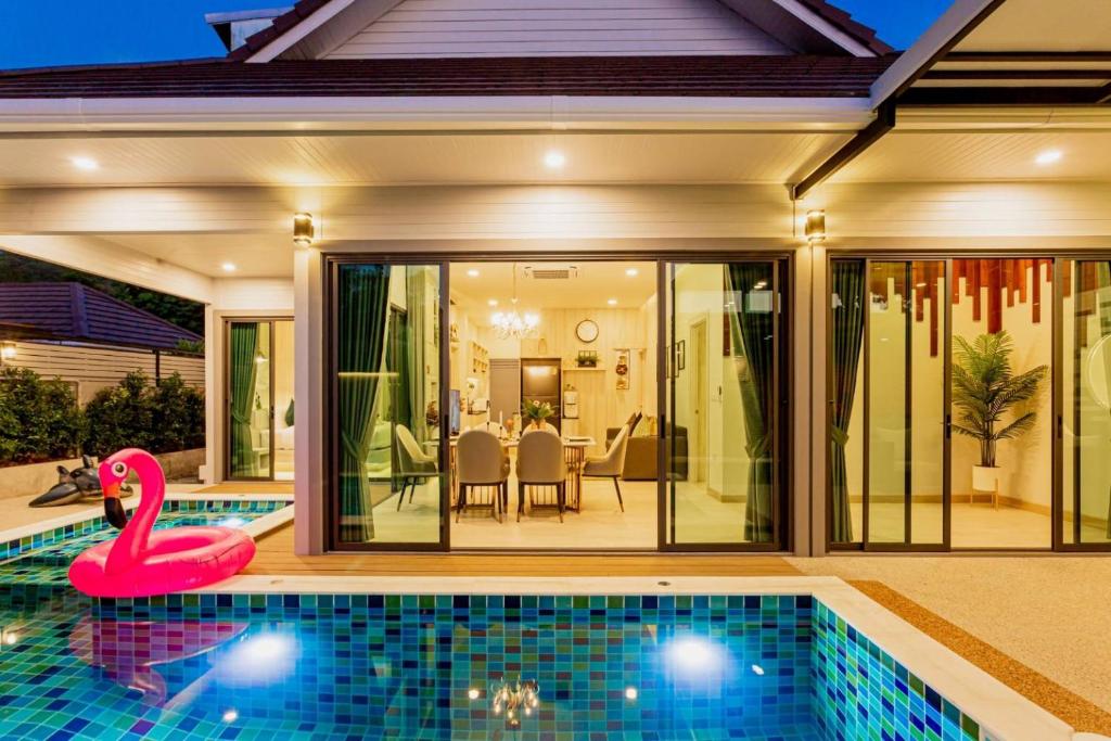 una piscina frente a una casa con un cisne rosa en Pool Villa No 10 by Duangtham, en Ban Khlong Haeng