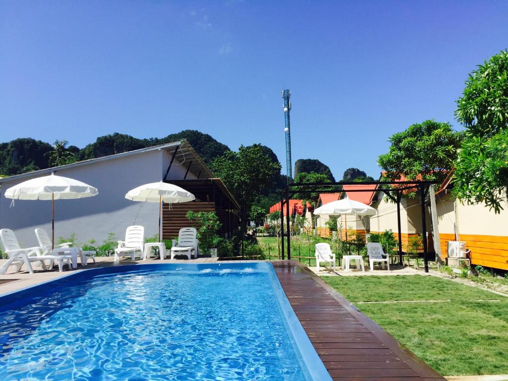 een zwembad met stoelen en parasols in een tuin bij The Hip Resort @ Phi Phi in Phi Phi Don