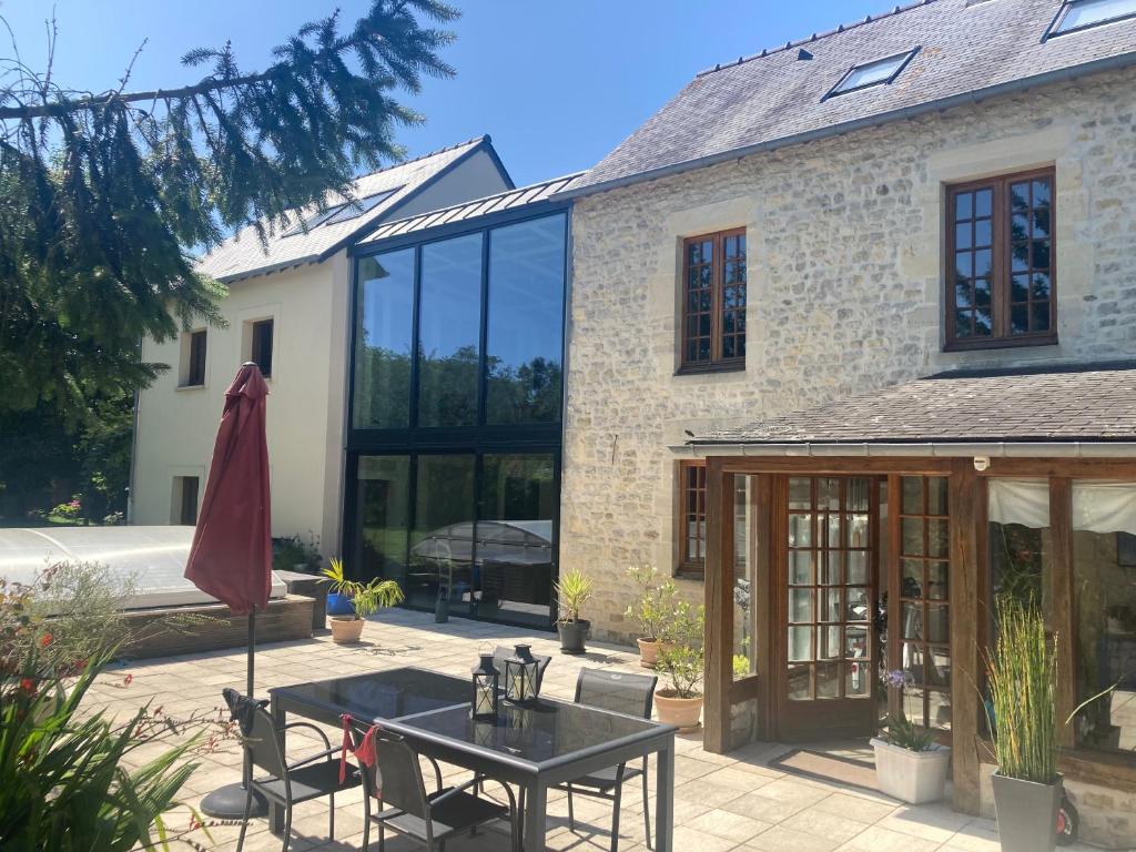 une maison avec des portes en verre et une table dans l'établissement Maison de bourg, à Carcagny