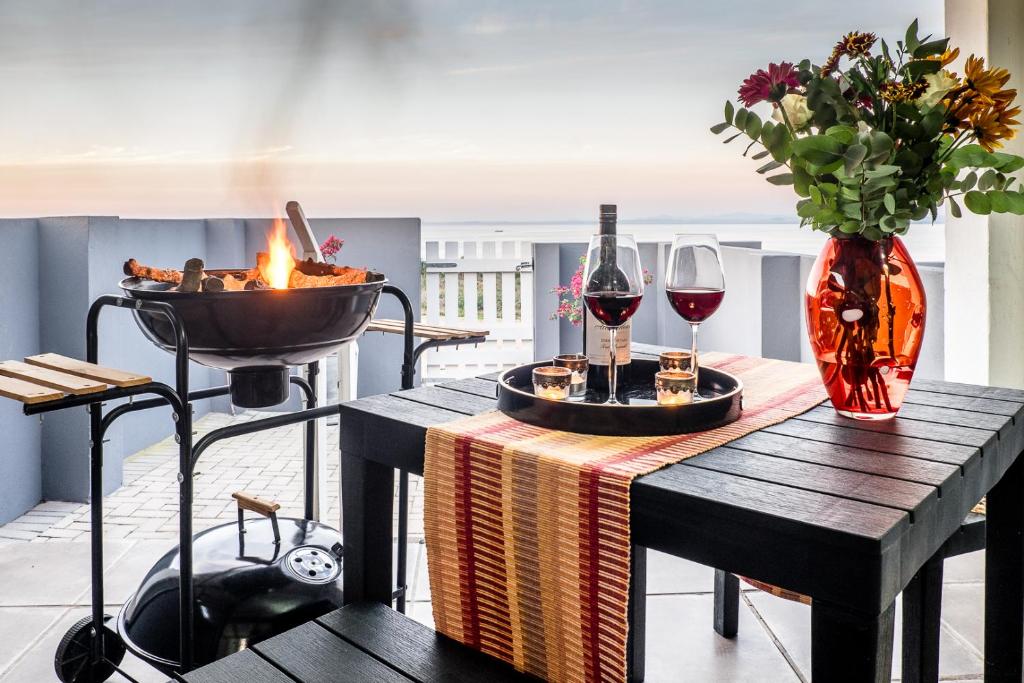 a table with two glasses of wine and a fire place at Sea Villa Vista in St. Helena Bay