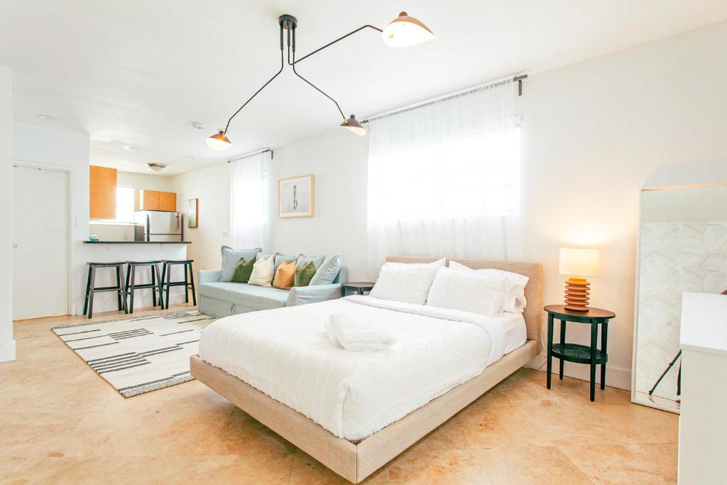 een witte slaapkamer met een bed en een bank bij Spacious Apt in the heart of South Beach in Miami Beach