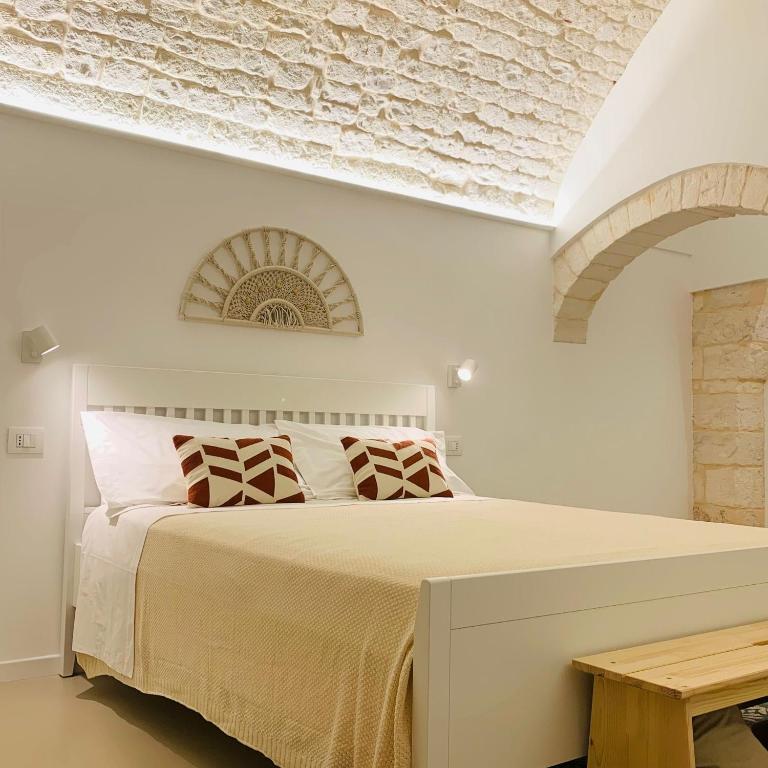 a bedroom with a large bed and a brick wall at Frida, suite in stile pugliese in Noci