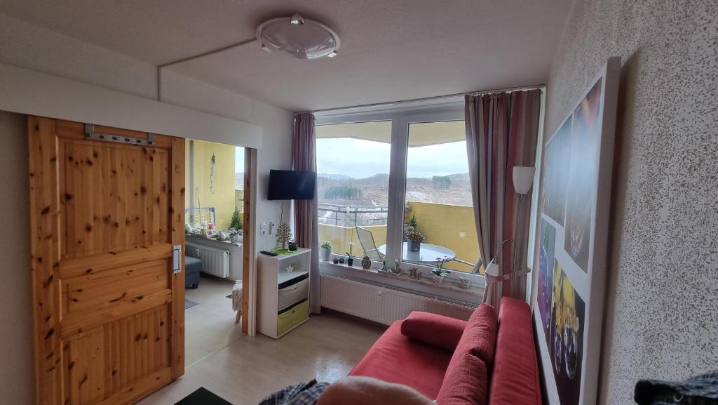 a living room with a red couch and a large window at Ferienwohnung Traumblick in Hohegeiß