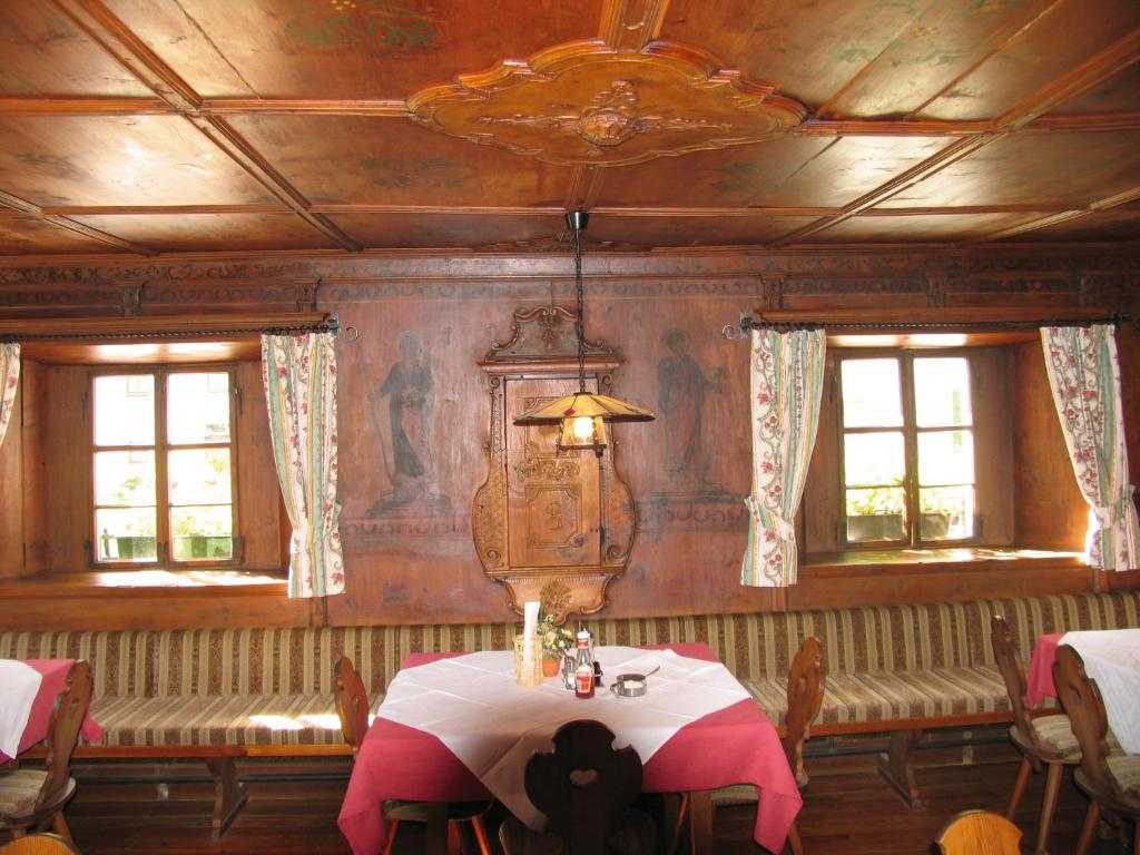 a dining room with a table and two windows at Hotel Bruggerwirt in Anterselva di Mezzo