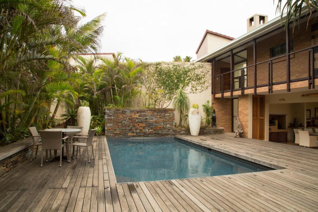 a backyard with a swimming pool and a wooden deck at Misty Blue Bed and Breakfast in Durban