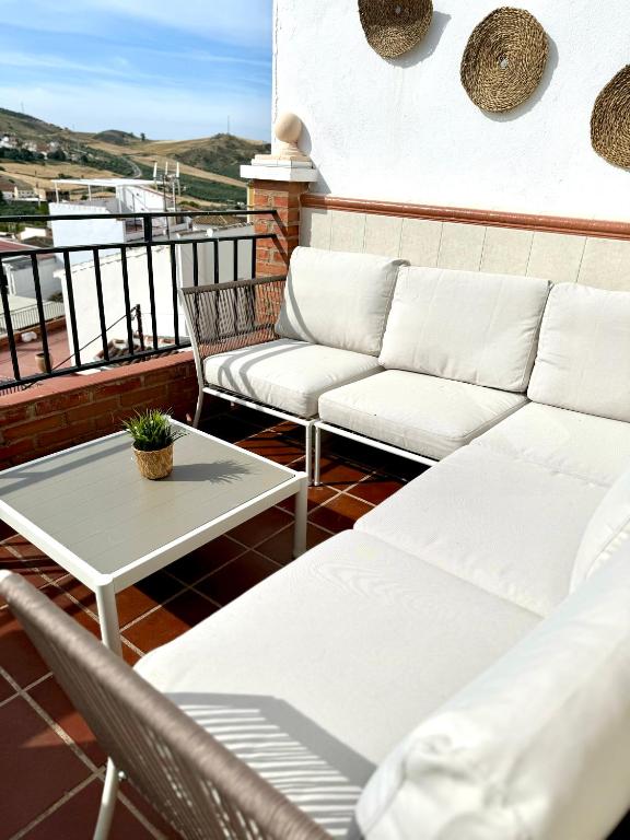 a balcony with white couches and a coffee table at Vistas del Valle in Valle de Abdalagís