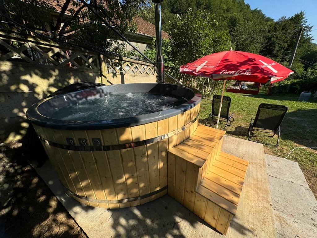 a hot tub with a bench and an umbrella at Casa- viata la tara in Bucureşci