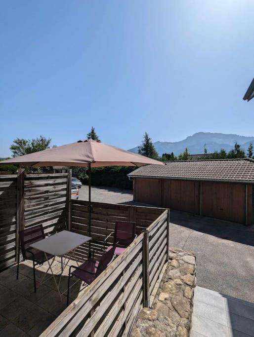un patio avec une table, des chaises et un parasol dans l'établissement Cabana & Studio Alpin Annecy - Terrasse Parking, à Argonay