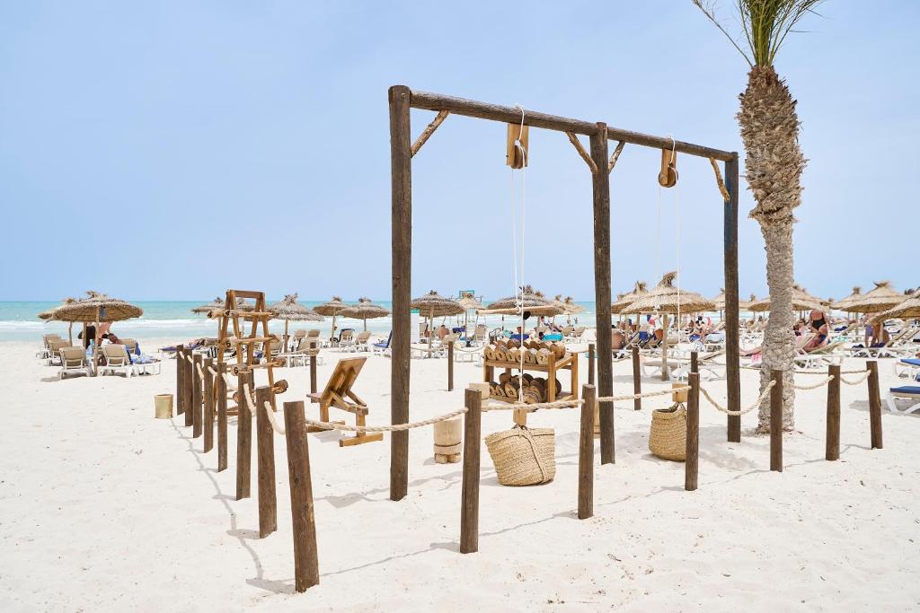 a beach with chairs and umbrellas and people at Iberostar Waves Mehari Djerba in Taguermess
