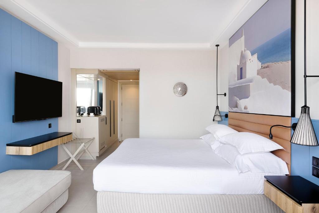 a bedroom with a white bed and a tv at Iberostar Waves Mehari Djerba in Taguermess
