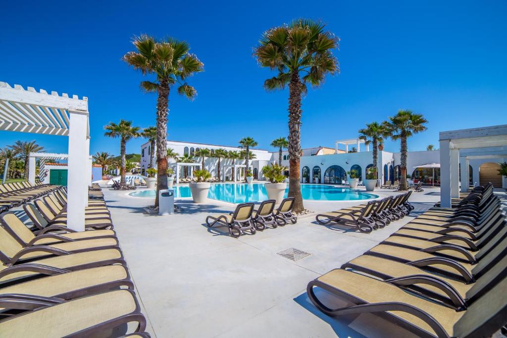 a swimming pool with chaise lounge chairs and palm trees at Centro Vacanze Poker in Casalbordino