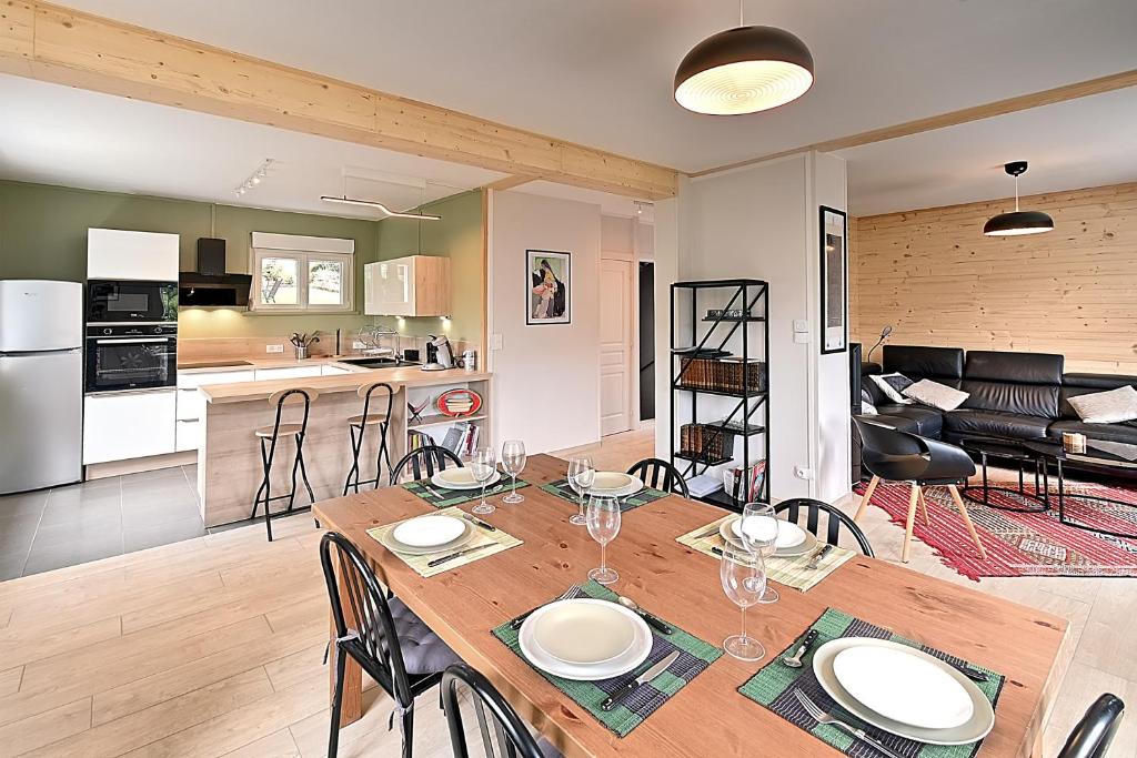 eine Küche und ein Wohnzimmer mit einem Holztisch und Stühlen in der Unterkunft Le Cocoon Clairefontaine - Maison vue montagne in Cornimont