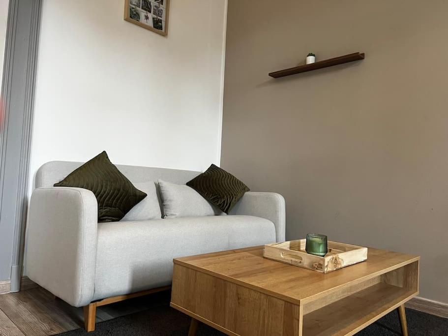 a living room with a couch and a wooden coffee table at Grand appartement avec jardin - Centre ville in Cambrai