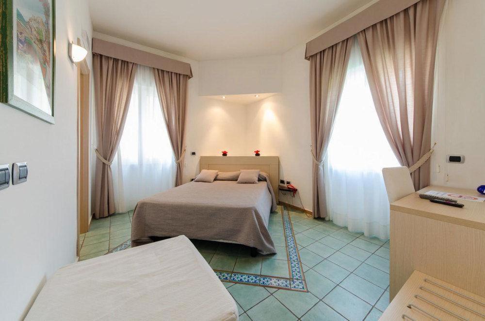 a bedroom with a bed and two large windows at Pietra di Luna residence in Maiori