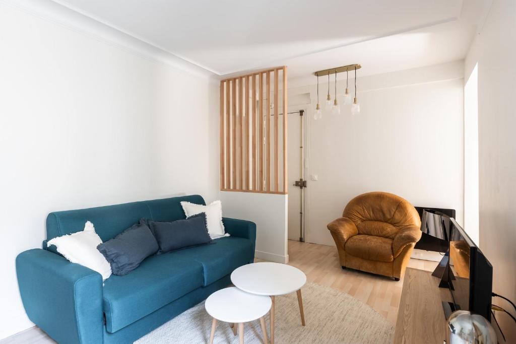 un salon avec un canapé bleu et une chaise dans l'établissement Appartement Hermosa - Welkeys, à Paris