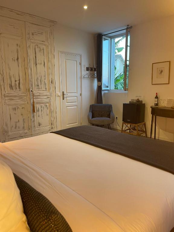 a bedroom with a large white bed and a chair at La Maison du Clocher in Saint-Émilion
