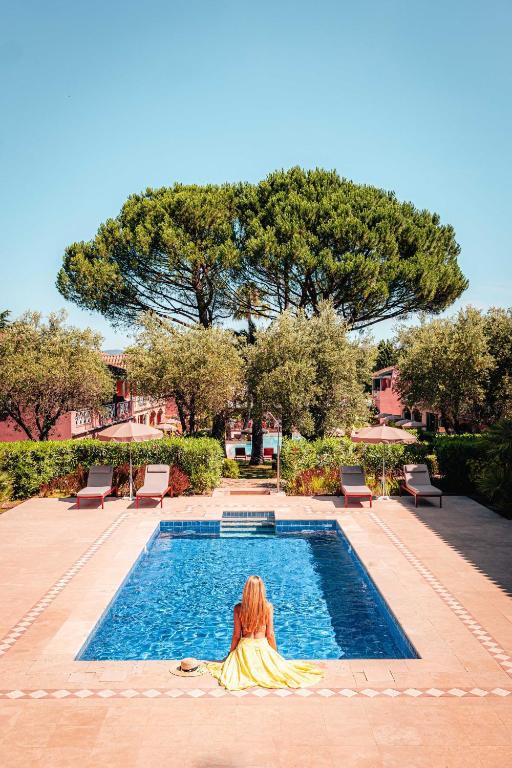 a woman sitting in front of a swimming pool at Domaine de l'Astragale in Saint-Tropez