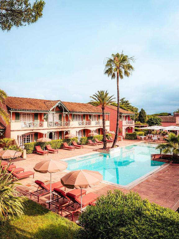a resort with a swimming pool with chairs and umbrellas at Domaine de l'Astragale in Saint-Tropez