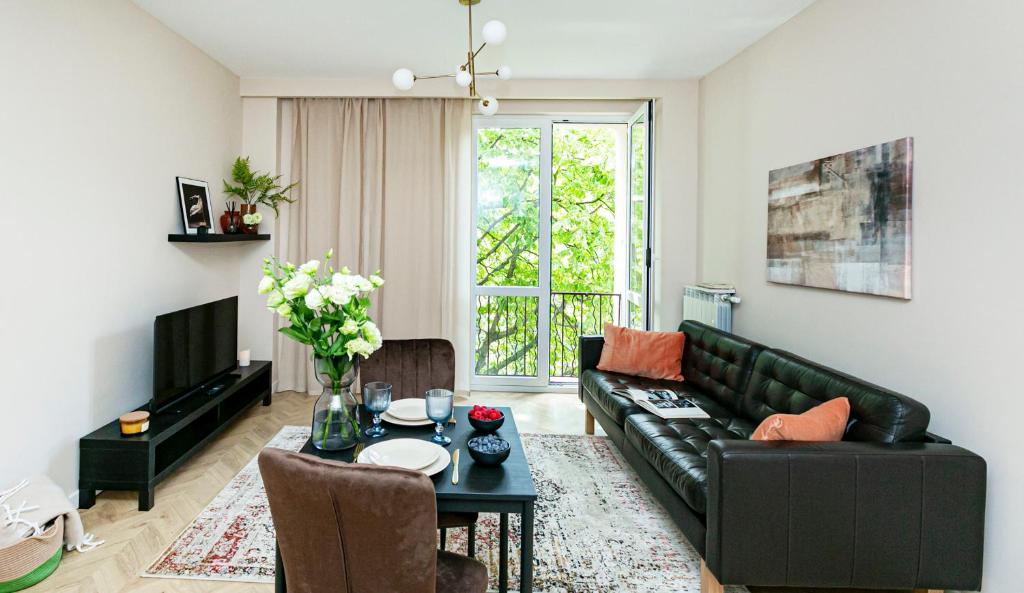 Una sala de estar con un sofá de cuero negro y una mesa. en Koszykowa 3 - Better Rental, en Varsovia
