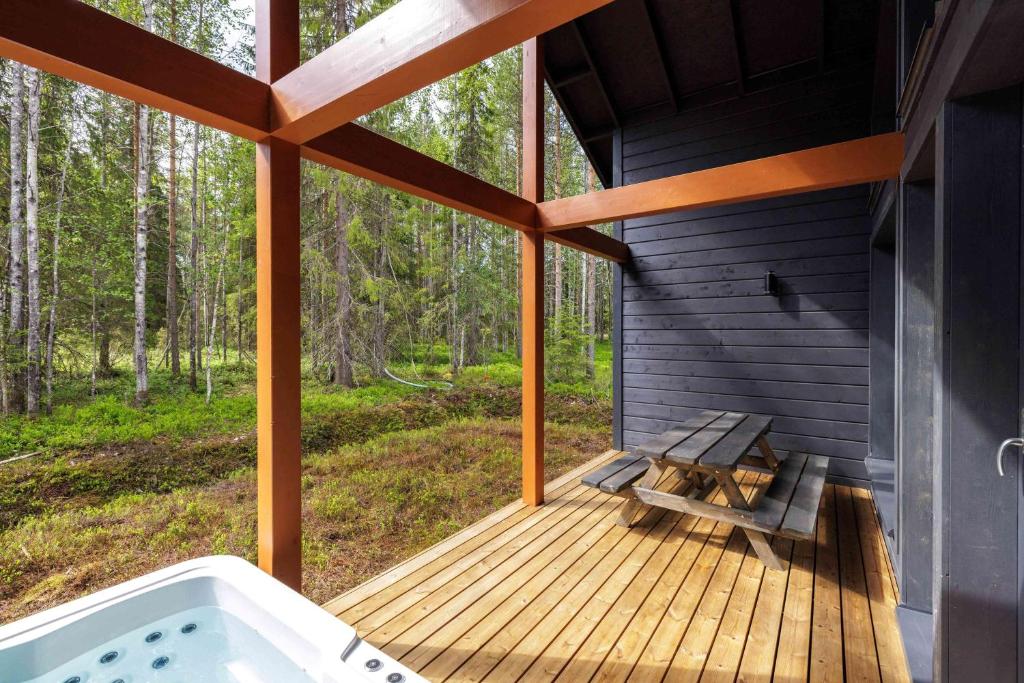 Un porche cubierto con jacuzzi y banco. en Syöte Ski Villa, en Syöte