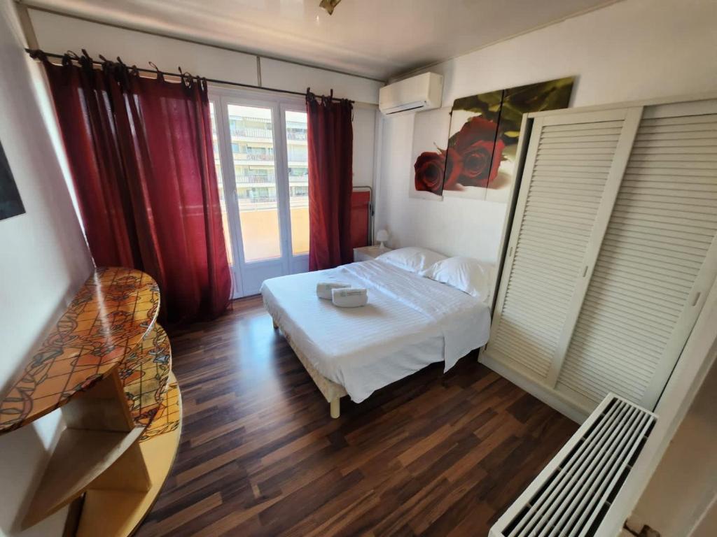 - une chambre avec un lit blanc et des rideaux rouges dans l'établissement A077 Appartement agreable avec vue mer et palais des festivals, à Cannes