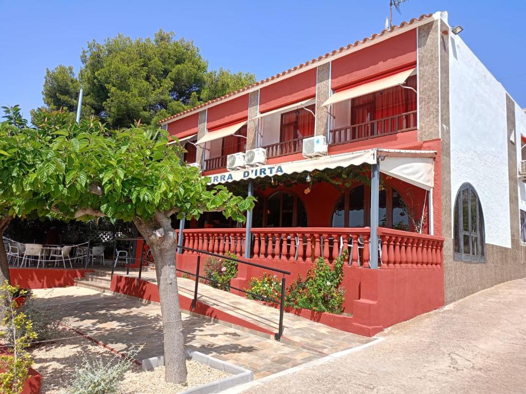 a red building with a tree in front of it at Hotel Serra D'írta in Alcossebre