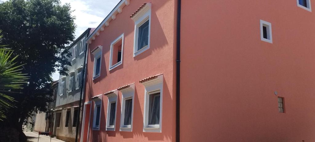 un bâtiment orange avec des fenêtres blanches sur une rue dans l'établissement Apartments Velo, à Veli Lošinj