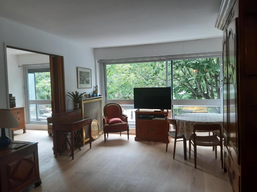 un salon avec une télévision, une table et des chaises dans l'établissement Charmant appart. ouest parisien, à Boulogne-Billancourt