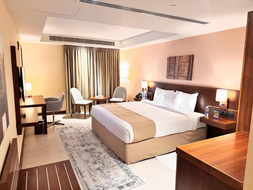 a hotel room with a bed and a desk at Kyriad Hotel Salalah in Salalah