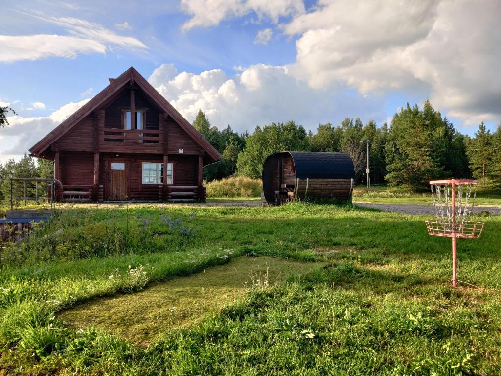 una casa di legno con una botte e un frisbee di Tapa Cottage next to disc golf. a Tapa
