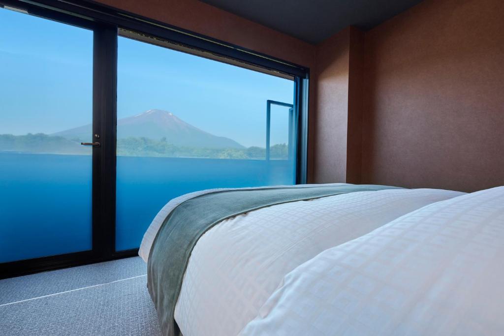 a bedroom with a bed and a large window at Mt Fuji View and Private Sauna Ryokan Shizuku in Yamanakako