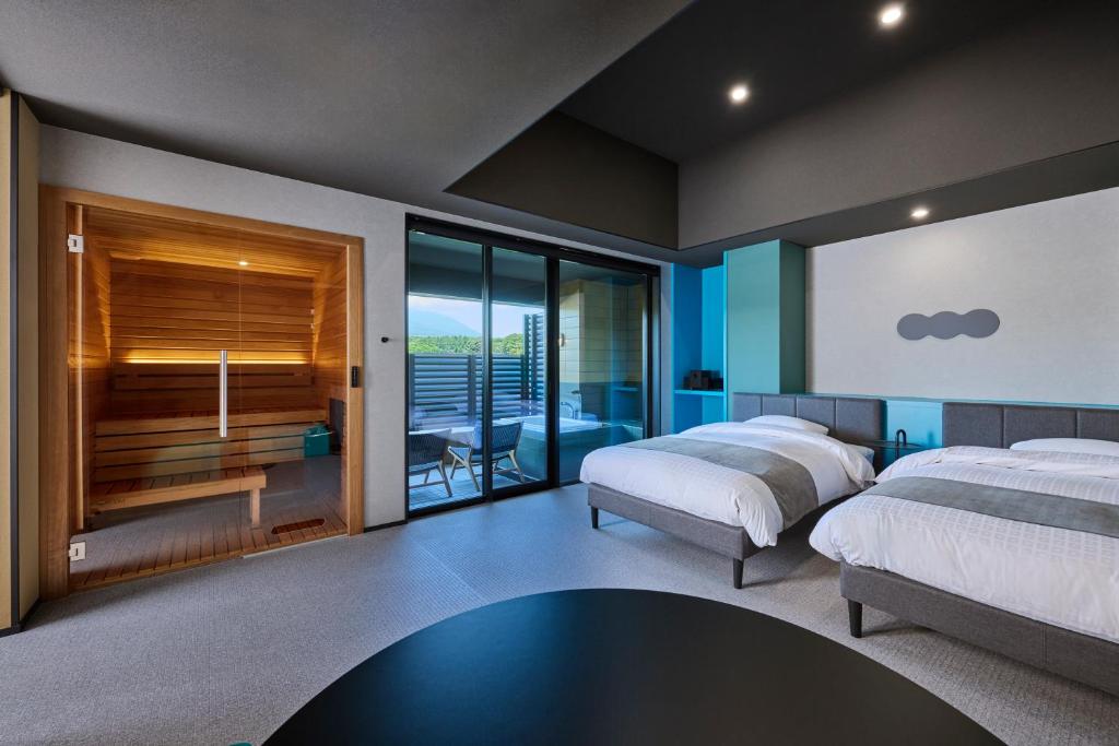 two beds in a bedroom with a balcony at Mt Fuji View and Private Sauna Ryokan Shizuku in Yamanakako