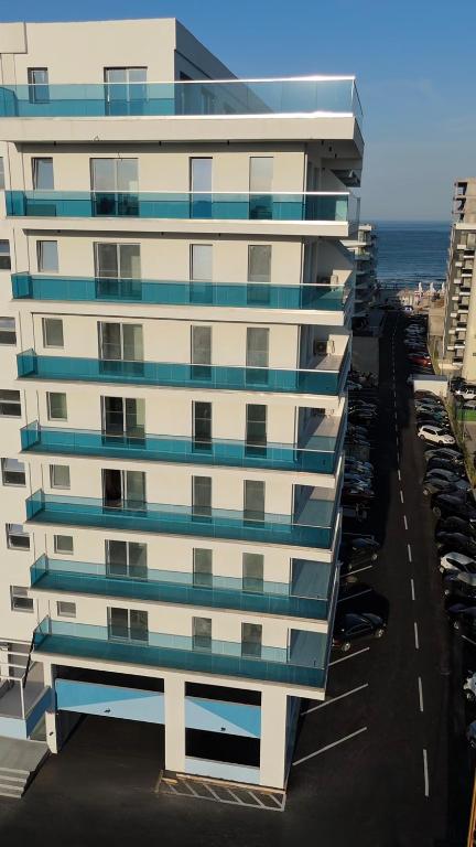 a tall white building with blue windows on a street at Wave 6 Apartments in Năvodari