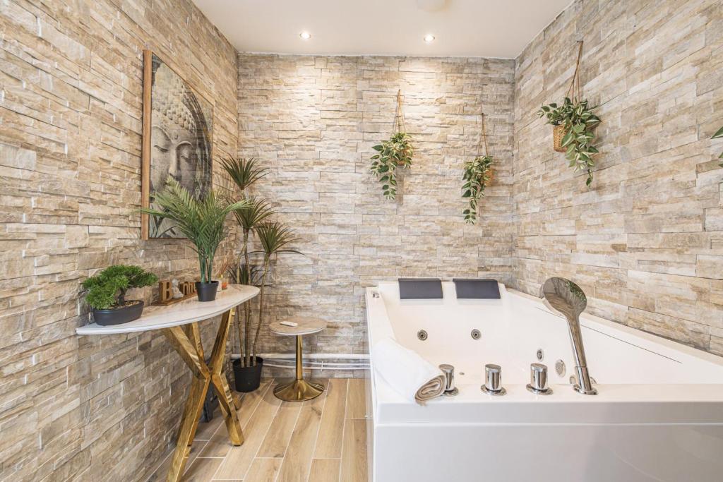 La salle de bains est pourvue d'une baignoire et d'une table avec des plantes. dans l'établissement Pentagone 1 SPA PRIVE, à Reims