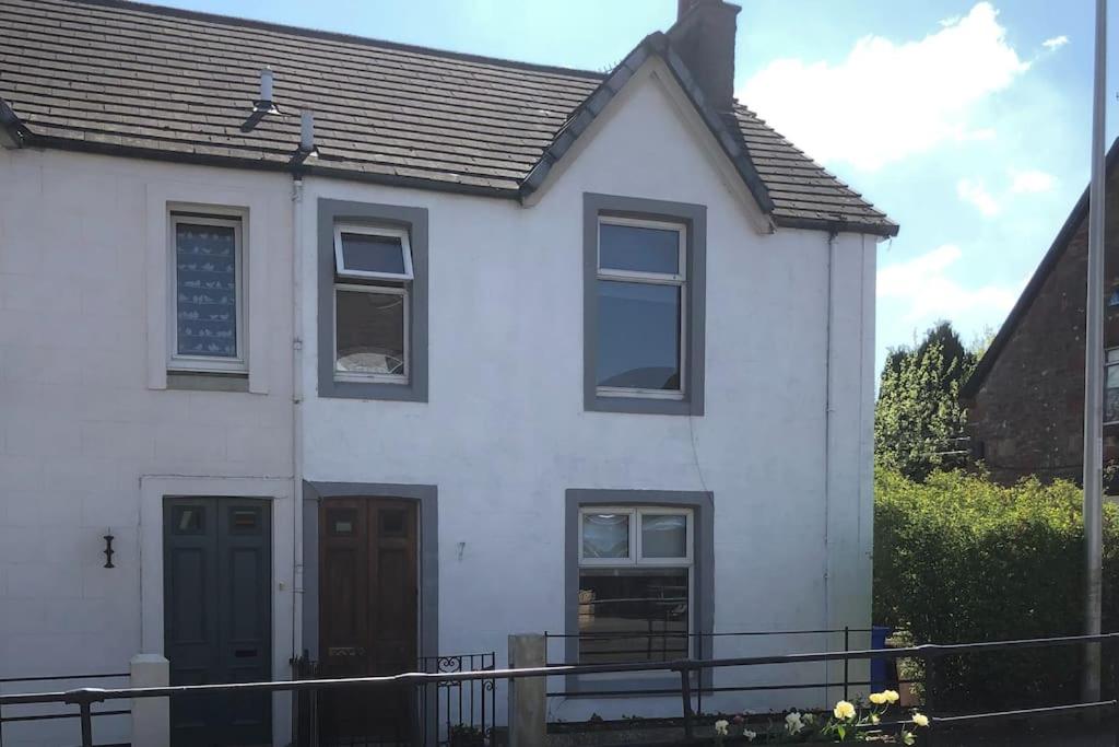 a white house with a black door and windows at House in Drymen Village with free local health club access in Glasgow
