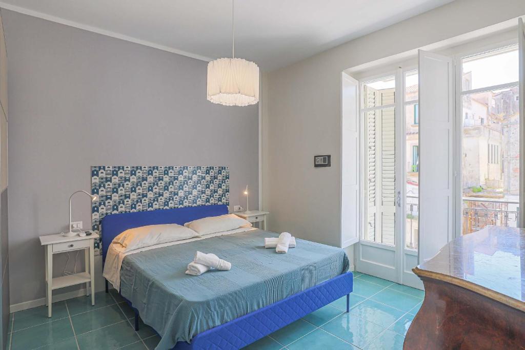 een slaapkamer met een blauw bed met handdoeken erop bij Amami Home in Salerno