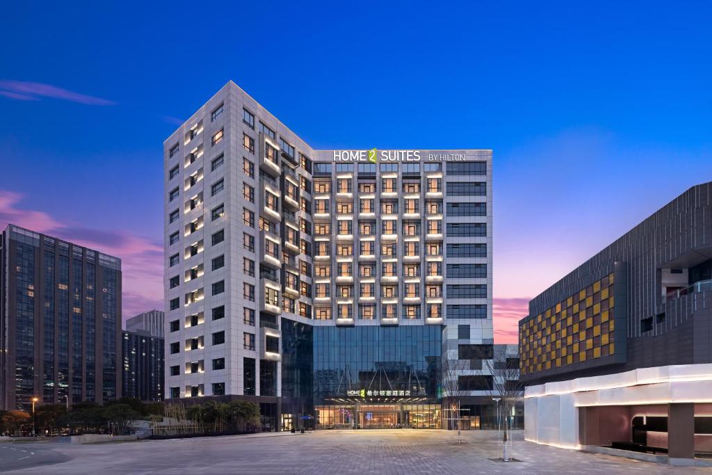 a tall building with a sign on top of it at Home2 Suite by Hilton Wuhan Economic Development Zone in Wuhan
