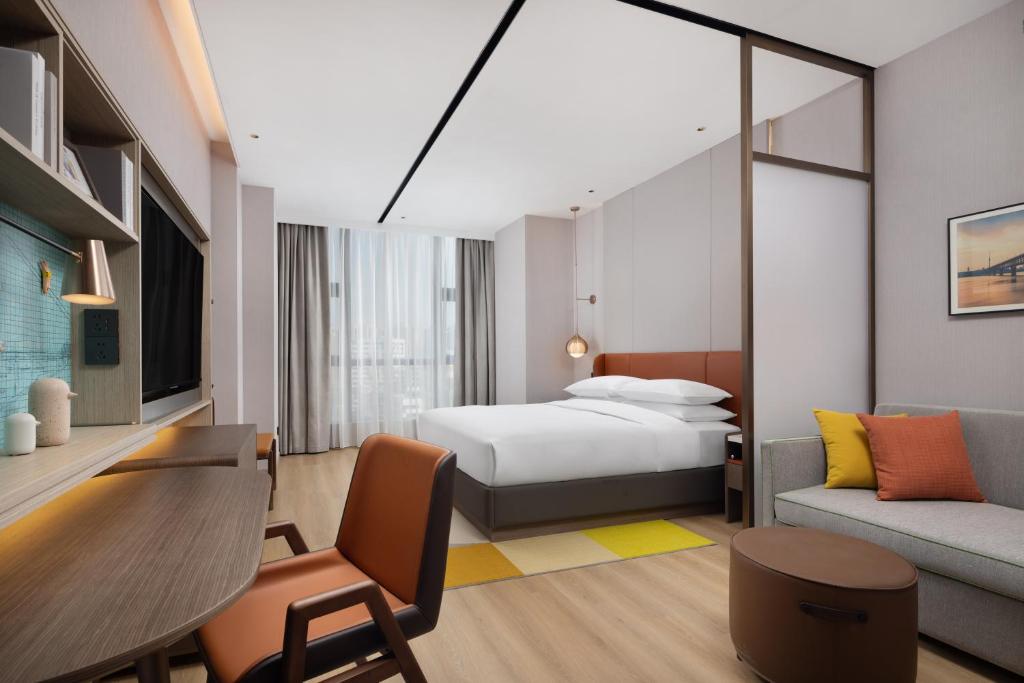 a hotel room with a bed and a couch at Home2 Suite by Hilton Wuhan Economic Development Zone in Wuhan